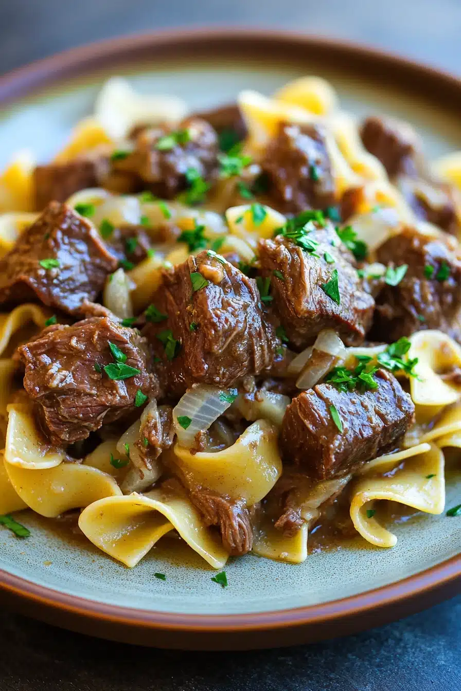 Close-up of slow cooker beef and noodles with a rich sauce and garnished with herbs.